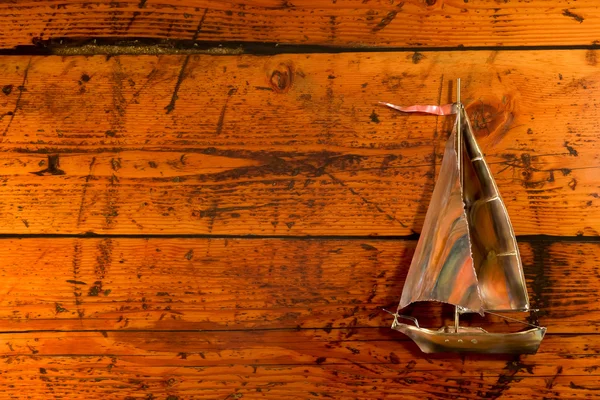 Koperen zeilboot op getextureerde hout — Stockfoto