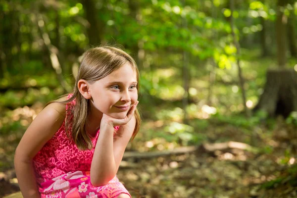 コピー スペースを見て森に座って幸せな若い女の子 ロイヤリティフリーのストック写真