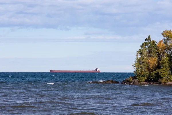 Great Lakes Freighter Passando por trás de uma ilha rochosa — Fotografia de Stock