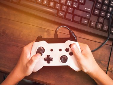 Küçük çocuk bilgisayarın önünde joystickle oynuyor.