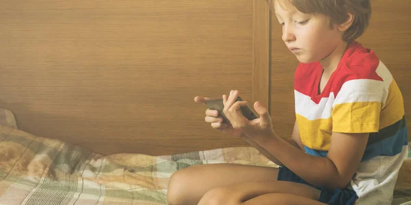 Kleiner blonder Junge spielt Spiele am Smartphone — Stockfoto