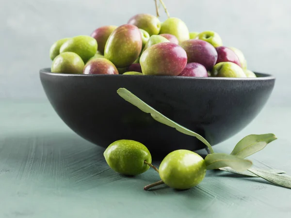 Freshly picked raw green olives in black bowl — Stock Photo, Image