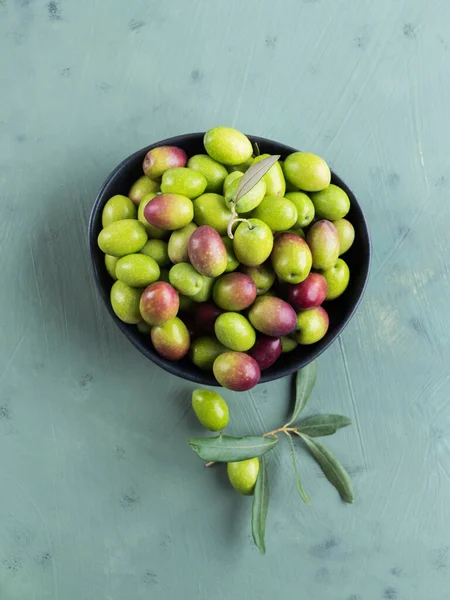 Nyplockade råa gröna oliver i svart skål — Stockfoto