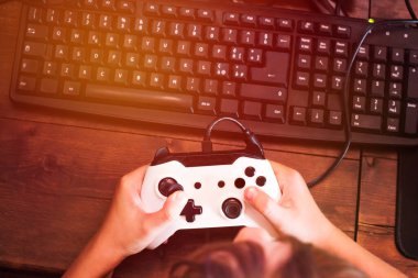 Küçük çocuk bilgisayarın önünde joystickle oynuyor.
