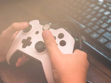 Küçük çocuk bilgisayarın önünde joystickle oynuyor.