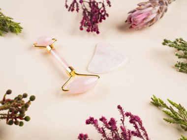 Çiçek arka planında kuvars guasha yüz silindiri