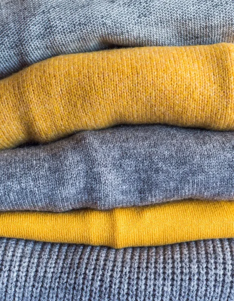 Sarı renkli ve gri kazaklı.