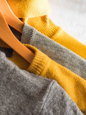 Sarı renkli ve gri kazaklı.