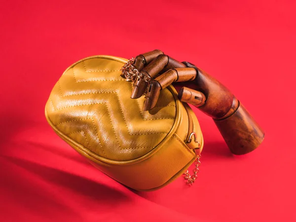 Bolso de mano de madera que sujeta cuero amarillo sobre rojo — Foto de Stock