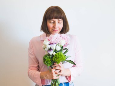 Güzel pastel şakayık buketi tutan genç bir kadın.