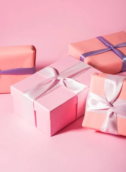 Рожеві загорнуті подарункові коробки зі стрічками на монохромному фоні — стокове фото