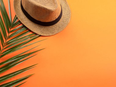 Hasır şapka ve eğreltiotu ile turuncu üzerine tatil konsepti