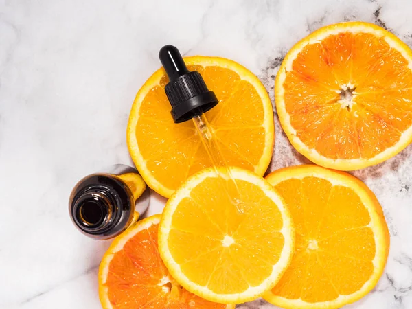 Vitamin C serum bottle with dropper on white marble background