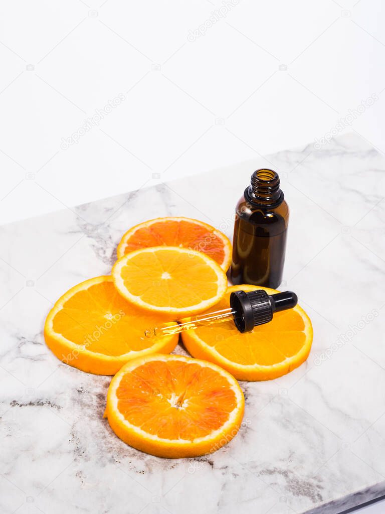 Vitamin C serum bottle with dropper on white marble background