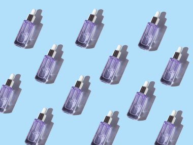 Hyaluronik glikolik asit serumu. Mavi pastel arka planda yaşlanmayı önleyen cam şişe.