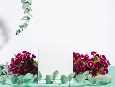 Botanik arka planda çiçekli beyaz küp podyumu