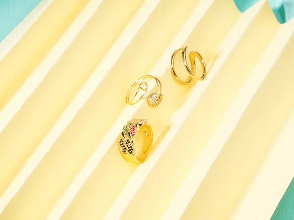 Aksesoris fashion cincin perhiasan emas pada latar belakang kipas kertas kuning — Stok Foto