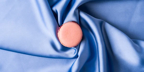 Pastelově růžové francouzské makróny na modrém hedvábí tkaniny pozadí — Stock fotografie