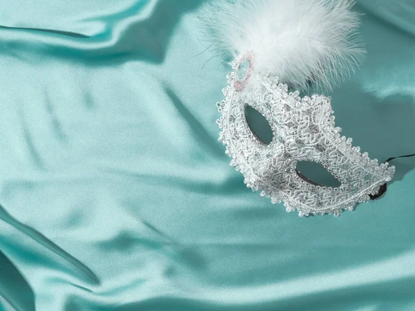 Bílá benátská karnevalová maska s peřím na zeleném saténovém textilním pozadí — Stock fotografie