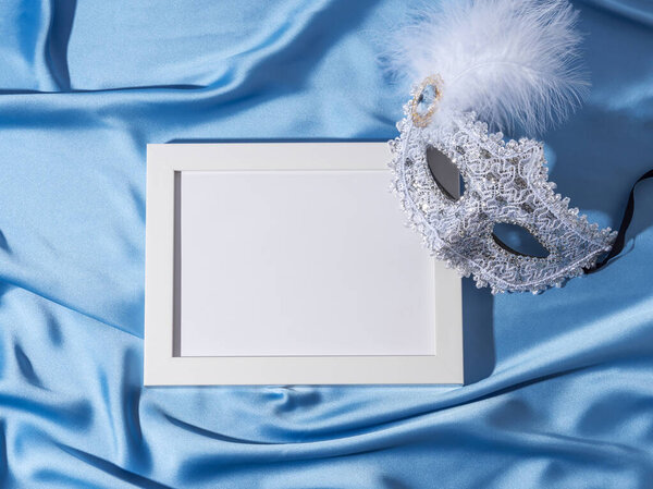 Карнавальная маска с пером на синем атласном фоне с белой рамкой для текста