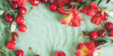 Kırmızı çiçekli kiraz çerçevesi ve doğal yeşil arka planda suda taç yaprakları