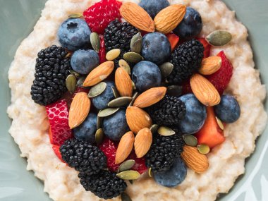 Lezzetli kahvaltılık yulaf lapası. Bitki sütü, fındık ve mermer masada böğürtlen.