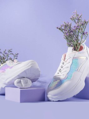 Mor arka planda çiçekli beyaz kadın spor ayakkabıları ve geometrik küp podyumu