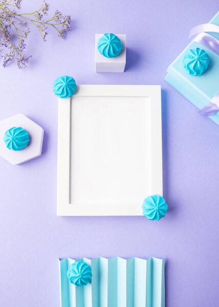 White empty frame on purple background with blue sweet decor, festive flat lay