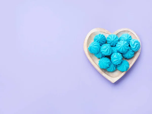 Дерев'яна тарілка у формі серця з блакитними солодкими обертаннями — стокове фото