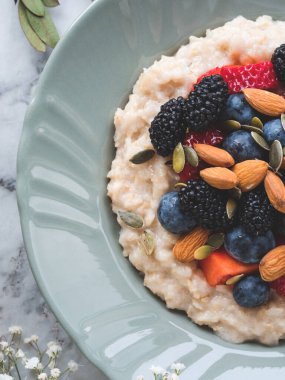 Lezzetli kahvaltılık yulaf lapası. Bitki sütü, fındık ve mermer masada böğürtlen.
