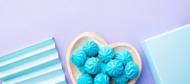 Kalp şeklinde mavi turkuaz pasta, hediye kutusu ve pastel mor arka planda dekor.
