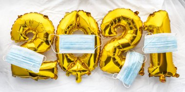 2021 yılbaşı sayıları altın folyo balonları beyaz çarşaflarda ve maskeli. Covid 'e veda ediyorum.