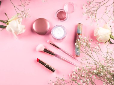 Pembe arka planda ürünlerle süslü moda fırçalar ve jigolo çiçekleri