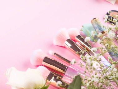 Pembe arka planda ürünlerle süslü moda fırçalar ve jigolo çiçekleri