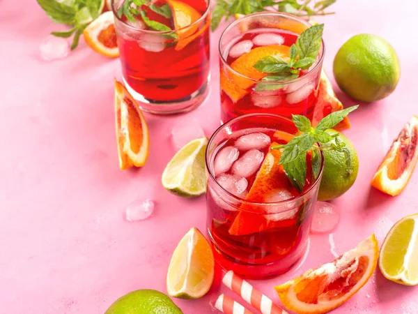 Erfrischender sommerroter Cocktail in Gläsern mit Blutorange und Limette auf rosa Hintergrund mit Minze — Stockfoto