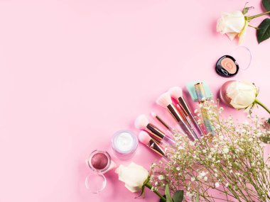 Pembe arka planda ürünlerle süslü moda fırçalar ve jigolo çiçekleri