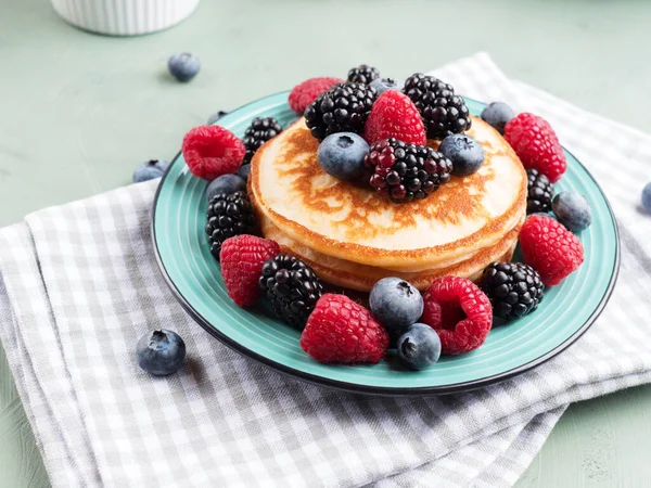 Stack of pancakes with raspberries and blueberries served with green tea — Stock Photo, Image