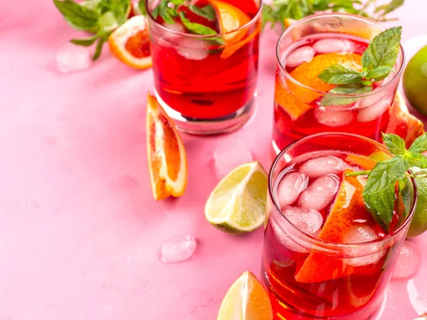 Erfrischender sommerroter Cocktail in Gläsern mit Blutorange und Limette auf rosa Hintergrund mit Minze — Stockfoto