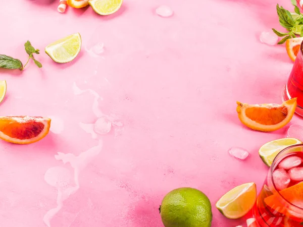 夏天的粉红色背景,有柑橘片,冰和薄荷叶.新鲜饮料鸡尾酒的配料 — 图库照片