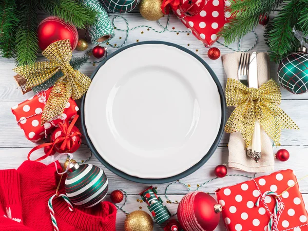 Χριστουγεννιάτικο εορταστικό τραπέζι με διακόσμηση και μαχαιροπήρουνα με χρυσό φιόγκο, άδειο λευκό πιάτο — Φωτογραφία Αρχείου