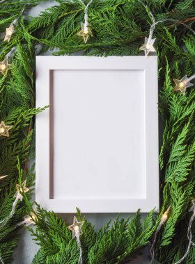 Yeşil köknar dallarının çerçevesi yıldız şeklinde Noel ışıkları ve beyaz boş tatil çerçevesi
