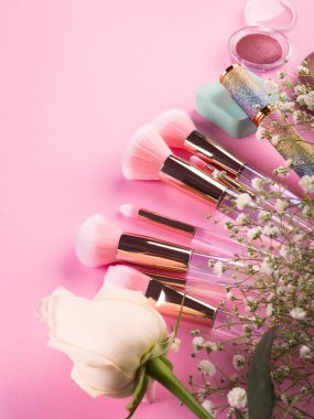 Pembe arka planda ürünlerle süslü moda fırçalar ve jigolo çiçekleri