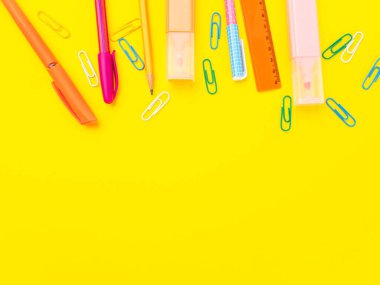 Okul konseptine geri dönelim. Sarı arkaplanda renkli yazma araçları
