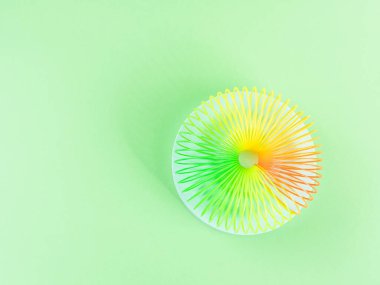 Renkli renkli gökkuşağı spiral plastik oyuncak yeşil arka planda podyumda