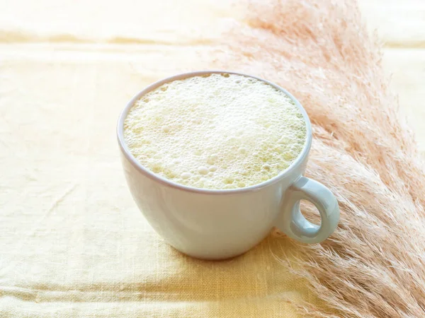 Matcha té latte mañana antioxidante bebida caliente en taza azul sobre mantel amarillo con hierba pampa — Foto de Stock