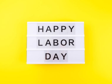 Sarı zemin üzerindeki beyaz ışık kutusunda İşçi Bayramınız kutlu olsun.