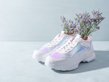 Turkuaz arka planda çiçekli pullu beyaz spor ayakkabılar