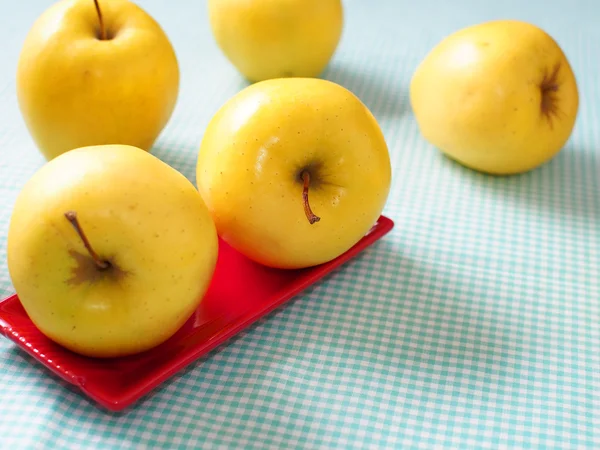 Yellow apples on red plate — Stock Photo, Image