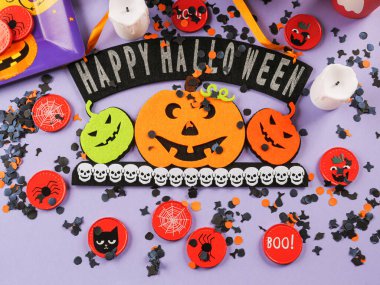 Happy halloween greetings decor with pumpkins on purple background with orange decor