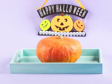 Halloween party decor with greetings of happy holiday with pumpkins on purple background